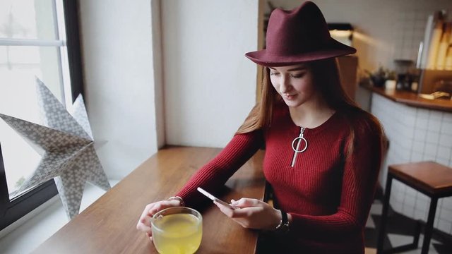 Beautiful young woman using smart phone sitting in loft coffee cafe