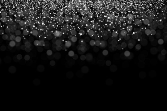 Silver glitter, snowing of grainy particles. Explosion of star dust with bokeh effect. Overlay texture, isolated on black background