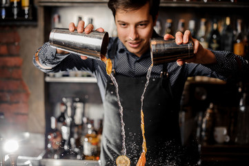 Bartender making a cocktail with slices of fresh orange fruit - obrazy, fototapety, plakaty