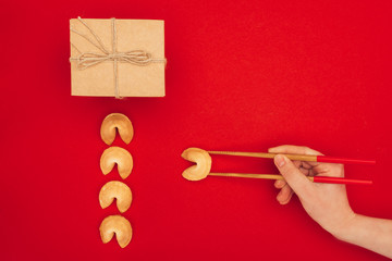 cropped shot of woman taking chinese fortune cookie with chopsticks, Chinese New Year concept