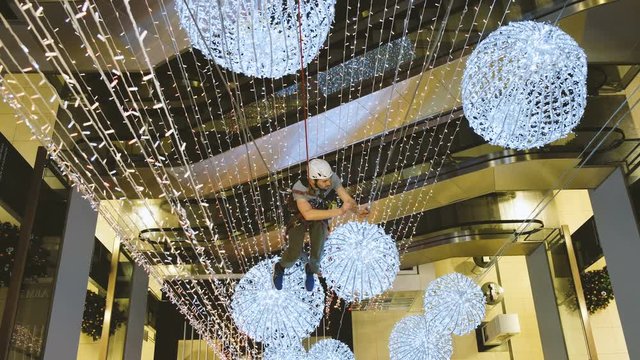 Industrial climber mounts Christmas decorations in the unsupported space in the shopping center