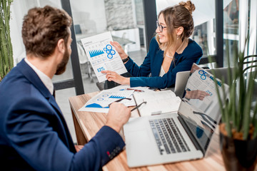 Analytic managers team working with paper charts and laptops at the office