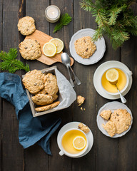The perfect tasty breakfast!)  Oatmeal cookies with chocolate in wooden box and green tea with lemon in mugs on a dark background with a Xmas tree. Best useful Cookies.  Flat lay, top view