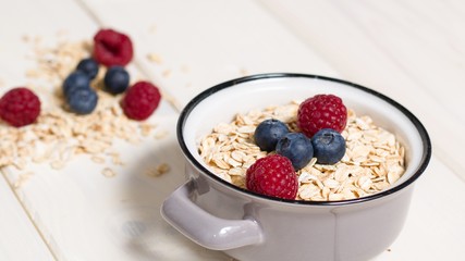 Oatmeal in small gray pot with raspberries and blueberries