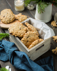 The perfect tasty breakfast!)  Oatmeal cookies with chocolate in wooden box and green tea with lemon in mugs on a dark background with a Xmas tree. Best useful Cookies.  Flat lay, top view
