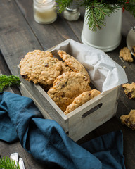 The perfect tasty breakfast!)  Oatmeal cookies with chocolate in wooden box and green tea with lemon in mugs on a dark background with a Xmas tree. Best useful Cookies.  Flat lay, top view