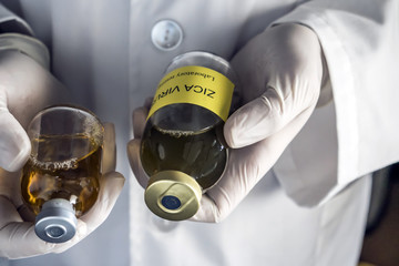 Doctor holds a sample vial of Zika virus in a hospital. Conceptual image