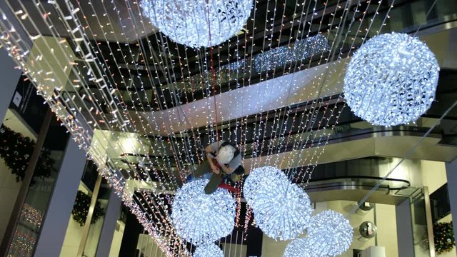 Industrial climber mounts Christmas decorations in the unsupported space in the shopping center