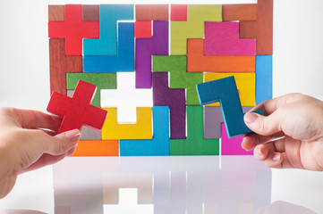 Concept of decision making process, logical thinking. Logical tasks. Conundrum, find the missing piece of the proposed. Hand holding wooden puzzle element. Hand sets the last element of the puzzle