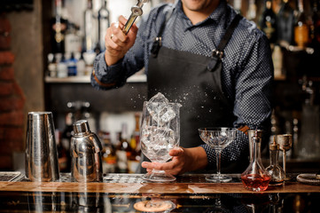 Bartender putting a big ice cube with help of special ice tongs
