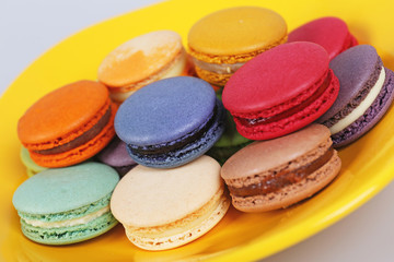 Fototapeta na wymiar Tasty delicious macaroons biscuits on yellow plate