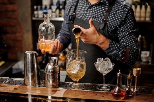 Barman pouring a portion of syrup into the large cocktail glass