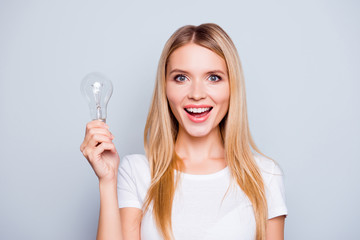 Wow! It is so easy! Close up portrait of cute lovely clever confident excited beautiful woman with blonde hair with open mouth, she is holding a light bulb, isolated on grey background