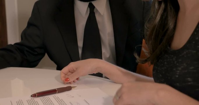 Woman signing paperwork contract and shaking hands with a man wearing mask