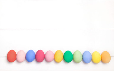 Easter composition with colored eggs on wooden white background with copy space.