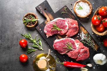 Raw beef steak with herbs and spices on stone background. Top view..