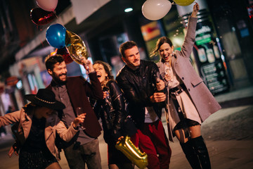 Group of happy friends going on the party, having fun at the street and drinking champagne. New year party. Birthday party 