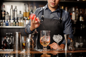 Barman pouring red fruit syrup into the large cocktail glass