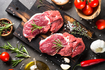Fototapeta na wymiar Raw beef steak with herbs and ingredients on cutting board. Top view.