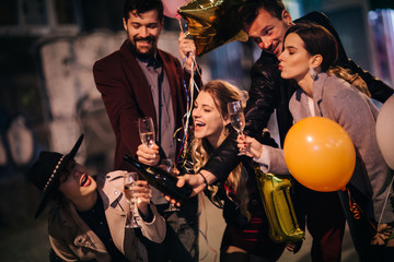 Group of happy friends going on the party, having fun at the street and cheering with champagne. New year party. Birthday party 