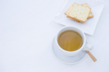 Hot tea in white ceramic cup and biscuit on white texture background, morning tea or afternoon tea break