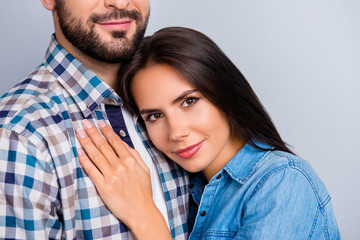 Close up cropped portrait of beautiful, pretty lovely, joyful, dreamy girl enjoying embrace with her bearded boyfriend, put head on his chest, couple in shirt over grey background