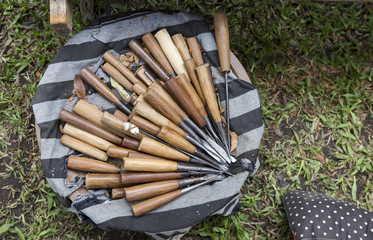 Wood carving tool on round shape wooden try cover with black and white cloth, tool display at the wood carving demonstration at the outdoor craft fair in Northern Thailand