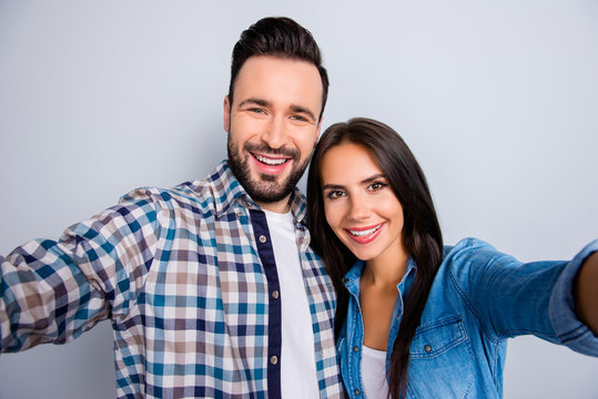  Close up portrait of young, caucasian, attractive, lovely, cute, sweet, smiling, positive  couple in shirts  making selfie on mobile phone over grey background