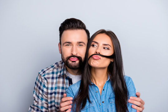 Comic, funky partners holding strand of hair with pout lips like mustache over grey background, fooling on valentine day