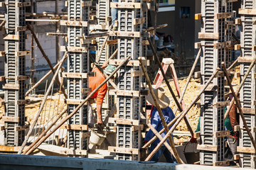 Worker pouring concrete to formwork at construction site to building house