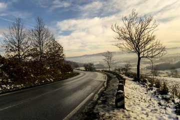 Obraz na płótnie Canvas foggy winter day over road through hills