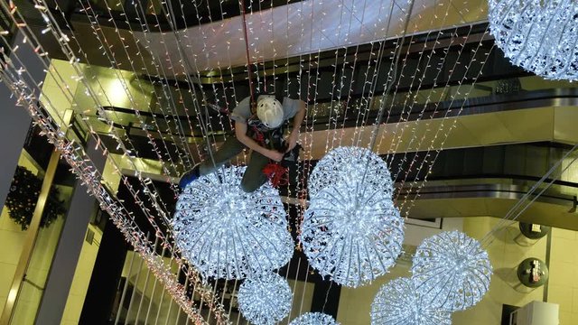 Industrial climber mounts Christmas decorations in the unsupported space in the shopping center