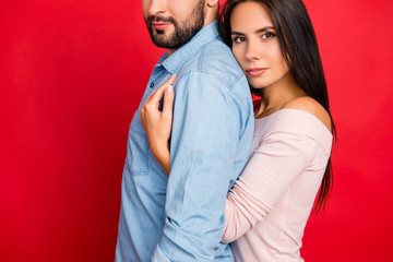 Fototapeta premium Cropped portrait, half face of man with bristle, woman embracing his lover from back with serious expression looking at camera over red background, tenderness, 14 february
