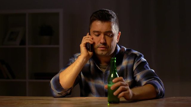 man drinking beer and calling on smartphone
