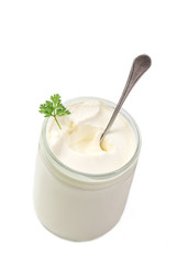 close up of sour cream pot with spoon and parsley in on white background top view