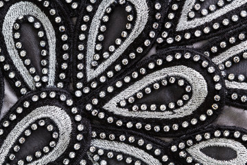 decorated fabric, a fragment of an evening dress embroidered with rhinestones as a background - obrazy, fototapety, plakaty