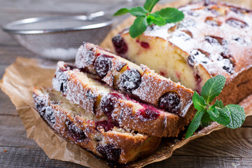 Slice of homemade cranberry cake with cherries, powdered sugar and mint
