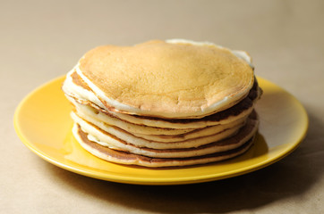 stack of pancakes on a yellow plate with honey
