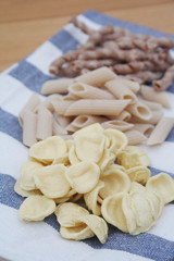 Variety of types of  traditional Italian pasta on wooden background