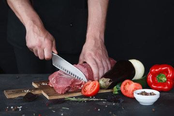 Chef cutting filet mignon on wooden board at restaurant kitchen