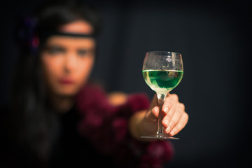 Glass with Absinthe. He holds a hand with a blurry woman