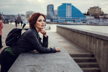 Young stylish woman wearing black coat, pants and handbag walking in the city street in fall season. Winter fashion, elegant look,. Plus size model.