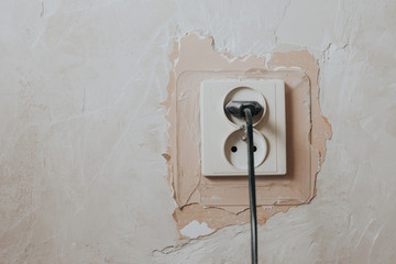 Electrical socket with plugged wire. Home renovation old dusty background with empty copy space.