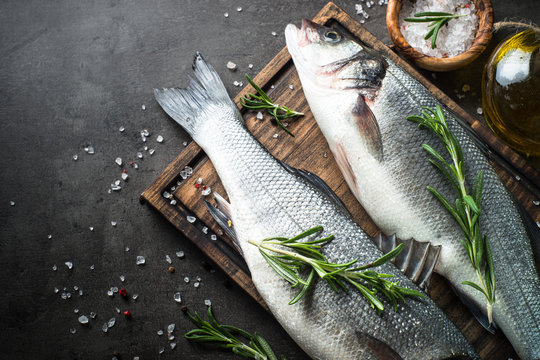 Fresh fish seabass on black stone table. Top vew.