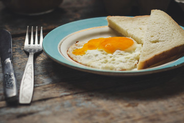 fried eggs with bread on a plate serving on a wooden table