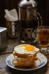 fried eggs with bread on a plate serving on a wooden table