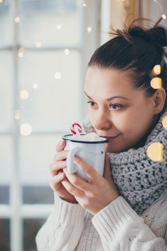 Close up of woman drinking hot chocolate next to the window. Winter theme 