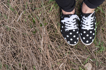 Legs in sneakers on a dry grass