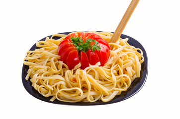 Pasta or spaghetti or vermicelli lie on a plate along with a tomato and seasoning food