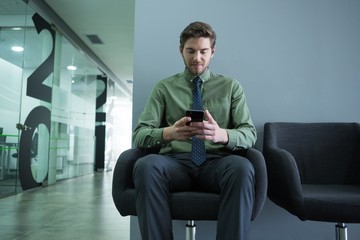 Naklejka na ściany i meble Male executive using mobile phone in waiting area
